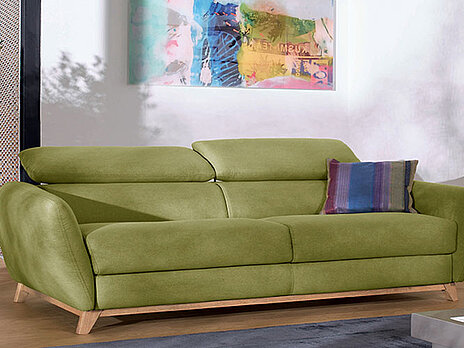 Kožna zelena sofa, sa podesivim glavonaslonima prikazana u ambijentu moderne sobe 